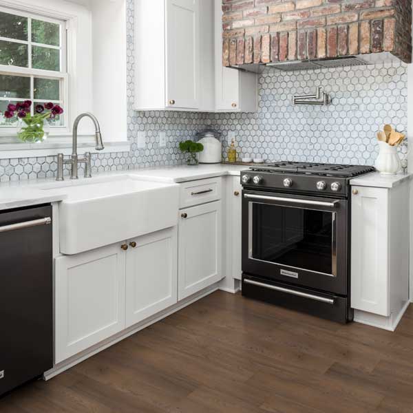 kitchen with deep sink, tile backsplash, wood look flooring and black chrome oven